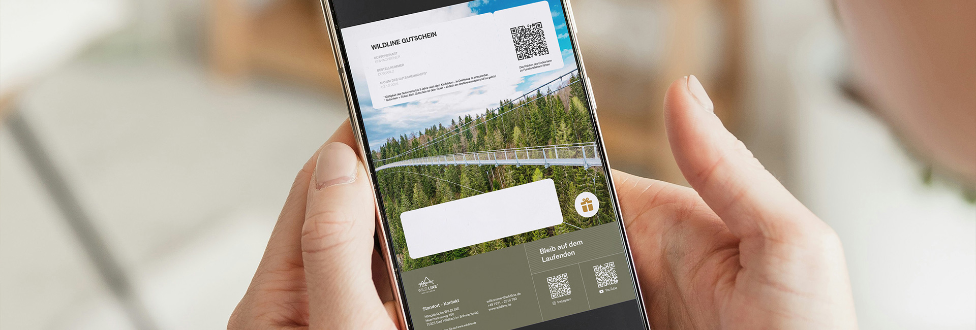 Zwei Hände halten ein iPhone mit dem digitalen Gutschein der Wildline in der Hand